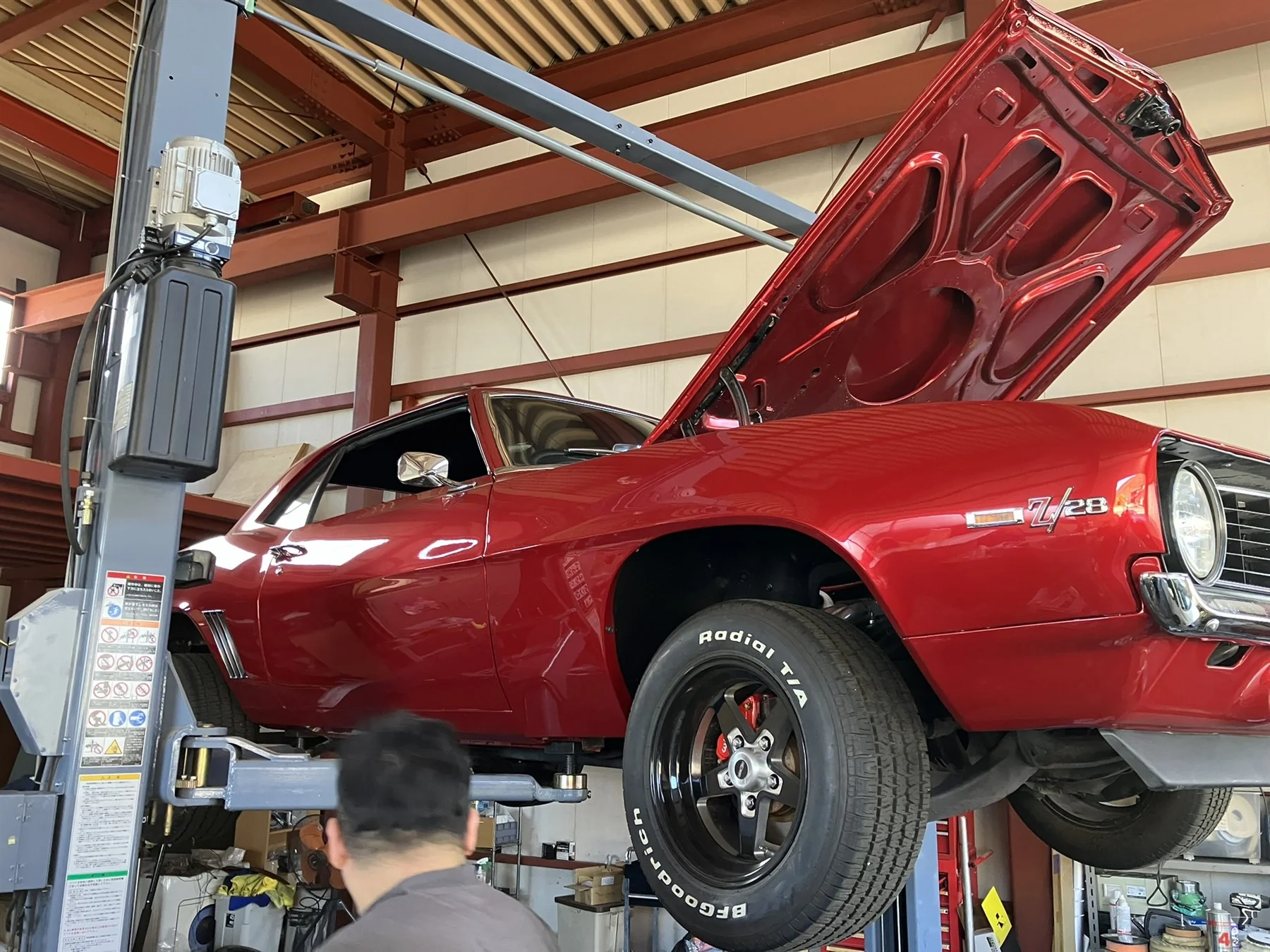 ナックスのガレージでリフトに上がる赤い車